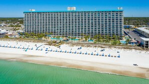 Un hotel grande con un extenso paseo marítimo, varias piscinas y un estacionamiento.
