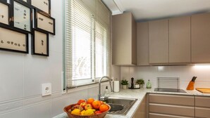 Une cuisine avec un plan de travail en marbre, un saladier rempli de fruits, un évier et des placards.