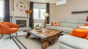 Un salon avec une cheminée, une horloge, un canapé et une table basse.