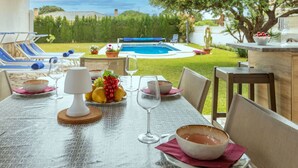 Un espace extérieur aménagé pour les repas, avec une piscine, des chaises et une table dressée pour un repas.