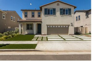 Stunning two-story home with a central entrance, garage, and beautifully manicured lawn.