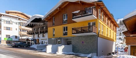 Hotel features a modern architectural style with wooden balconies and a distinctive yellow facade.