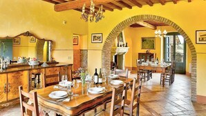 A dining area with a wooden table set for a meal, a chandelier, and a brick fireplace.