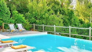 A swimming pool with lounge chairs and a wooden deck.
