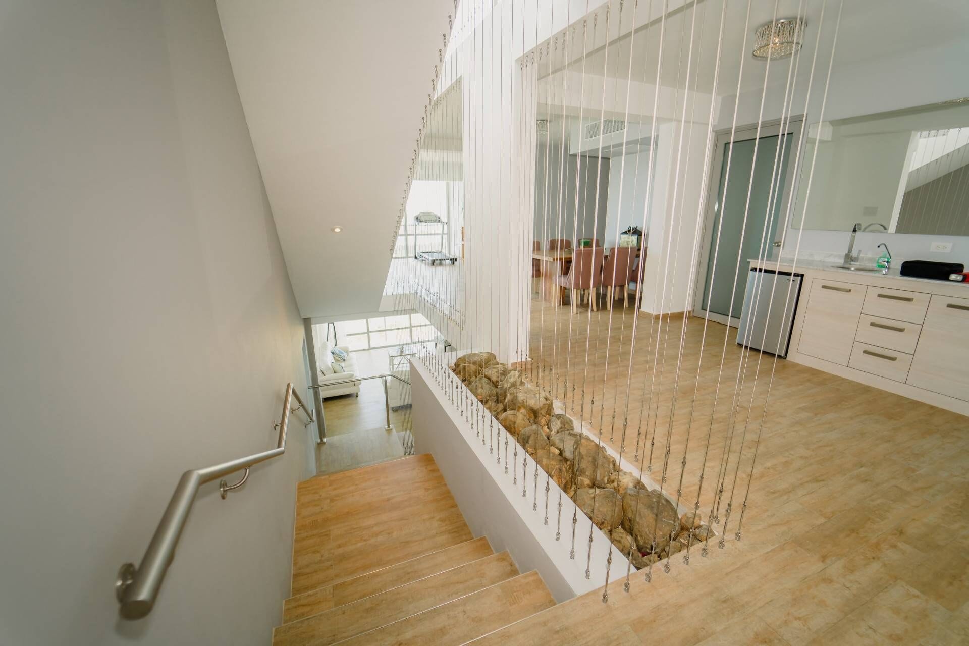 A modern interior with a wooden staircase, a kitchen area, and a dining space.