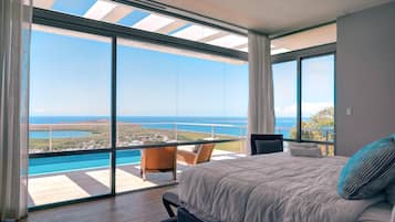 Ein Schlafzimmer mit einem großen Bett, Meerblick und einem Balkon mit Pool.