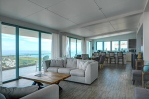 A spacious living area with a large sofa, a coffee table, and a dining area with bar stools. - 5BR Villa | Private Pool + Walk-Out Kitchen | Near Seven Seas Beach | Sleeps 14 (Fajardo)