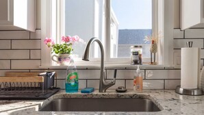 A kitchen with a stainless steel sink, a window with a view, and various kitchen items on the counter. - charming 2-bedroom pioneer home near brian head ski resort and national parks in parowan, utah (Parowan)
