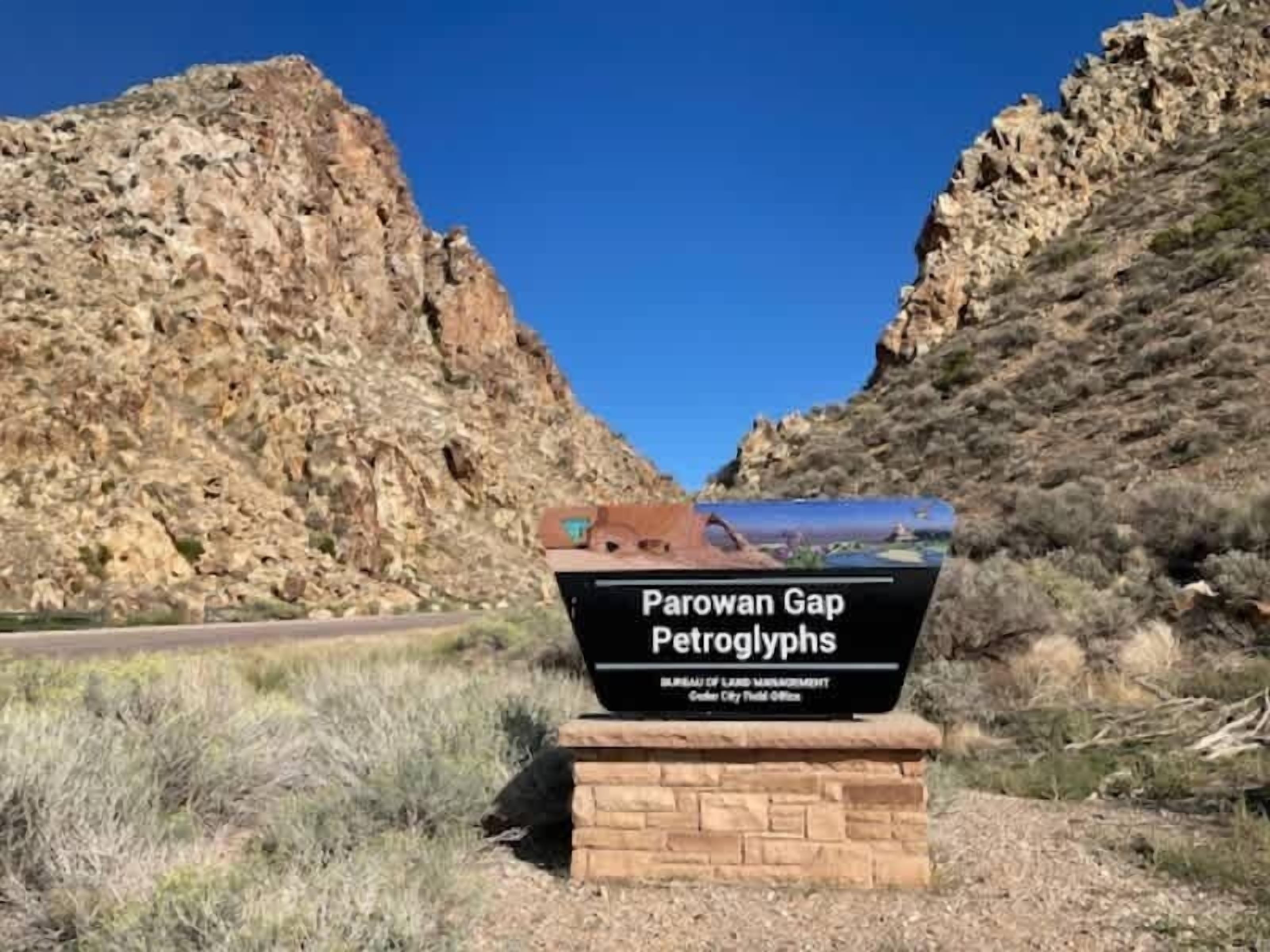Schild für die Parowan Gap Petroglyphen mit freiem Blick auf die umliegende felsige Landschaft.