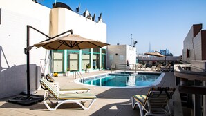 A rooftop pool area with lounge chairs, umbrellas, and a clear blue sky. - WESCOTT PEARL HOTEL APARTMENTS (Dubai)