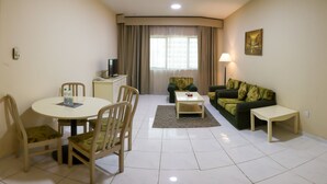 A living room with a dining table, chairs, a sofa, a coffee table, and a TV. - WESCOTT PEARL HOTEL APARTMENTS (Dubai)