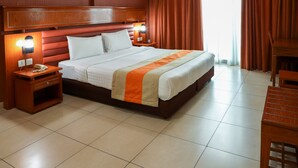 A hotel room with a large bed, wooden headboard, two bedside tables with lamps, a wooden nightstand, and a desk with a chair. - WESCOTT PEARL HOTEL APARTMENTS (Dubai)