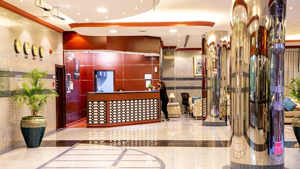 A hotel lobby with a reception desk, seating area, and decorative pillars. - WESCOTT PEARL HOTEL APARTMENTS (Dubai)