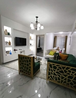 Relax in this stylish living room with a flat-screen TV, green sofa, and matching armchairs.