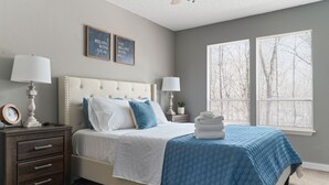 A bedroom with a bed, two bedside tables, a nightstand, a window with blinds, and two wall-mounted pictures. - Pool Table-Hot springs Village Cozy Twnhse+Walk 2 lake (Hot Springs village)