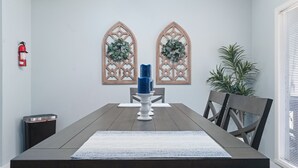 A dining area with a wooden table, two chairs, a blue candle holder, and two decorative wall panels. - Pool Table-Hot springs Village Cozy Twnhse+Walk 2 lake (Hot Springs village)