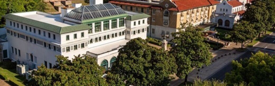 Un edificio grande y blanco con techo verde y un invernadero de vidrio.