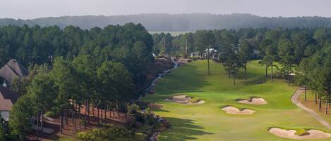 A golf course with a pond, sand bunkers, and a clubhouse.