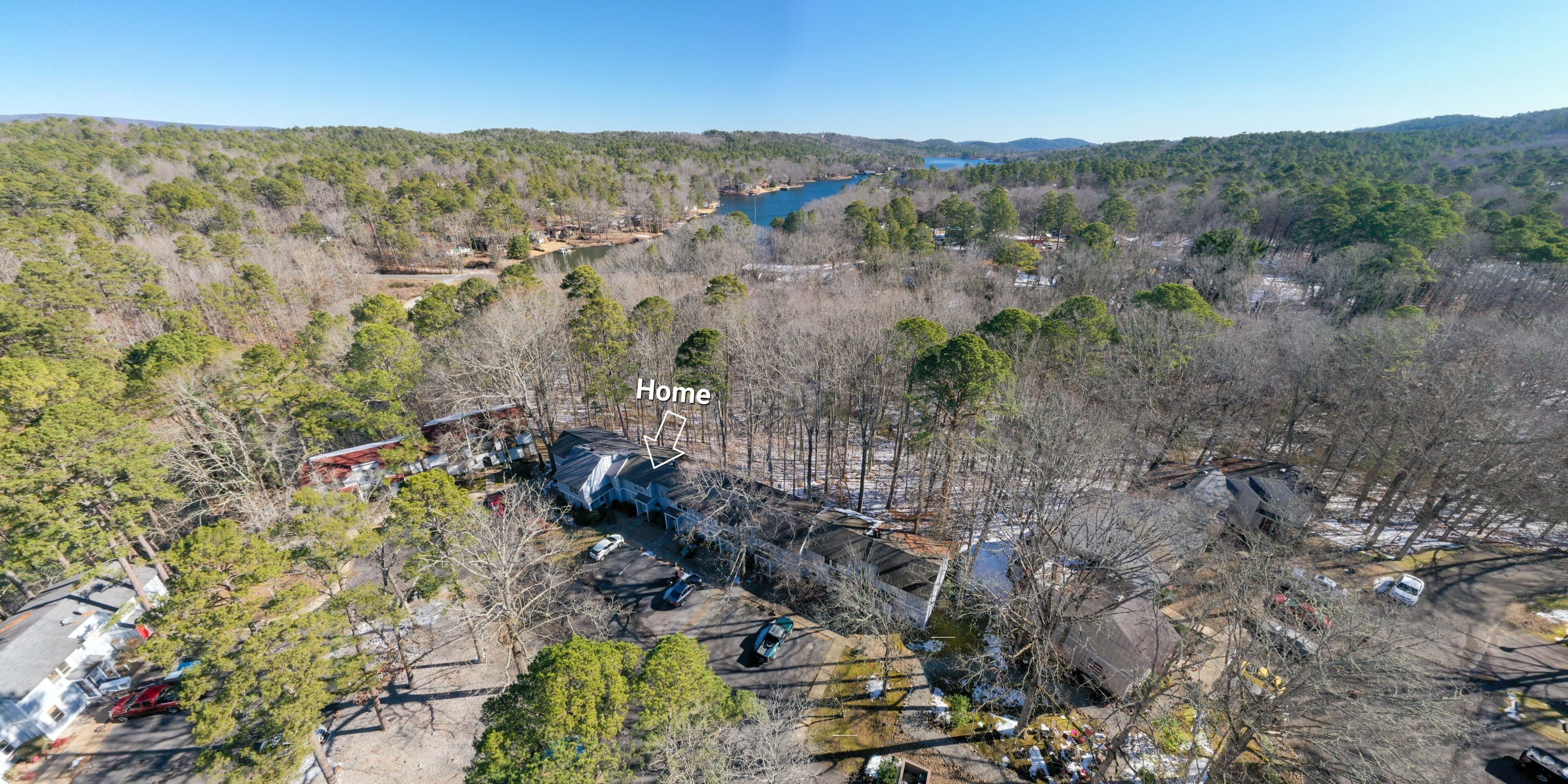 Una vista aerea di una zona residenziale con case, un lago e una foresta circostante.