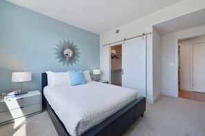 Un dormitorio con cama, mesitas de noche, armario y espejo en la pared.