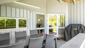 A covered patio area with a table and chairs, a grill, and a view of the outdoors. - 3 bedroom cozy home in Højslev (Højslev)