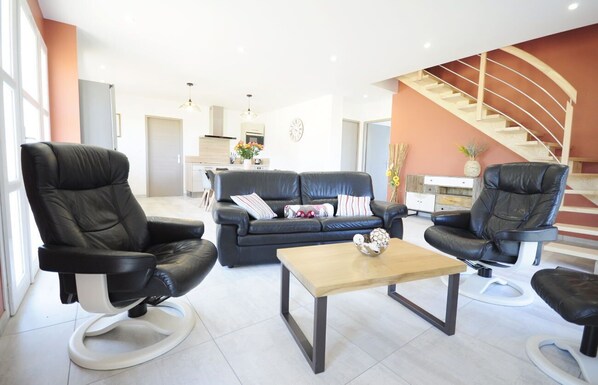 A modern living room with a sofa, two black leather chairs, and a coffee table. - LA GRANGE DE NESPES ( 12 pers-) ( Classified 4 stars) (Air-conditioned) (Vailhourles)