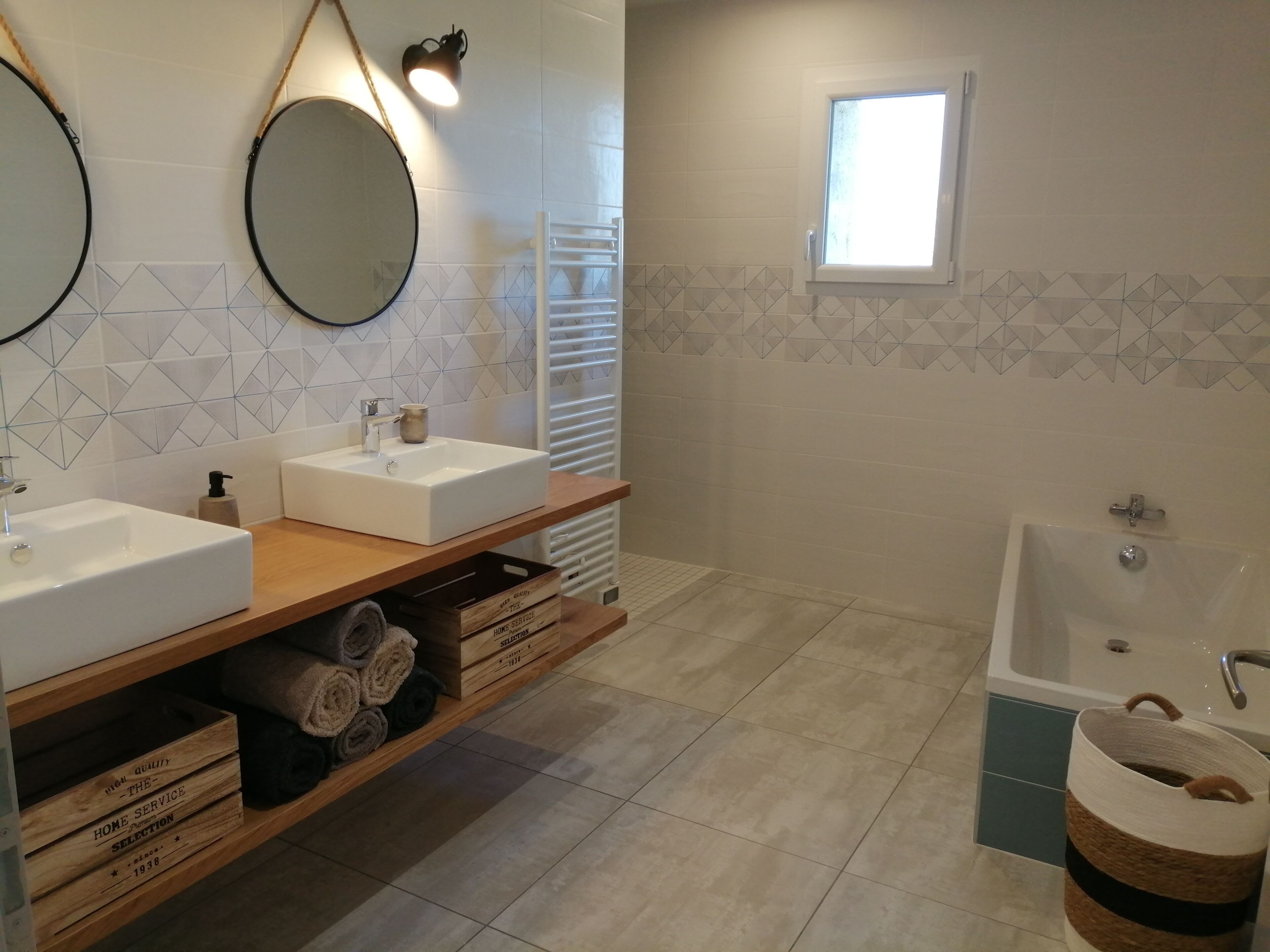 Un baño moderno con dos lavamanos, un espejo grande, una ventana y una bañera.