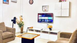 A modern living room with a flat-screen TV, comfortable sofas, a coffee table, and a decorative vase.