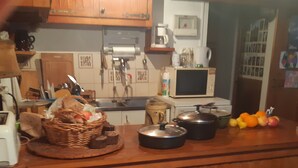 Eine Küche mit Holzausstattung, einer Mikrowelle und einem Spülbecken. Auf der Arbeitsfläche liegen Früchte und ein Korb.