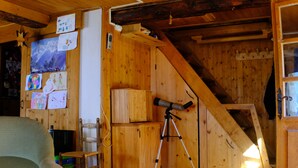 Ein Holzblockhaus Innenansicht mit einem Teleskop, Holzwänden und verschiedenen Kinderzeichnungen.