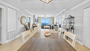 A spacious dining area with a long wooden table, white chairs, and a decorative mirror on the wall. - Ocean Ritz 1503 • Luxury Beachfront Retreat (Panama City Beach)