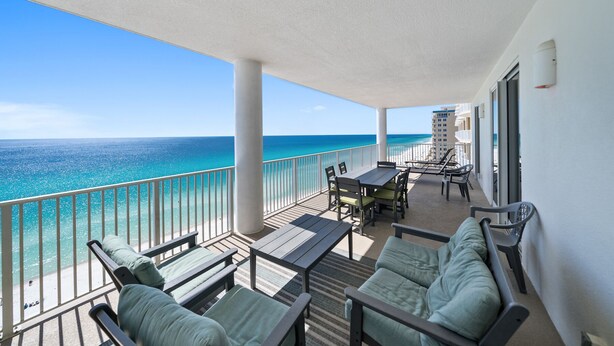 A balcony with a view of the ocean, furnished with chairs and a table. - Ocean Ritz 1503 • Luxury Beachfront Retreat (Panama City Beach)