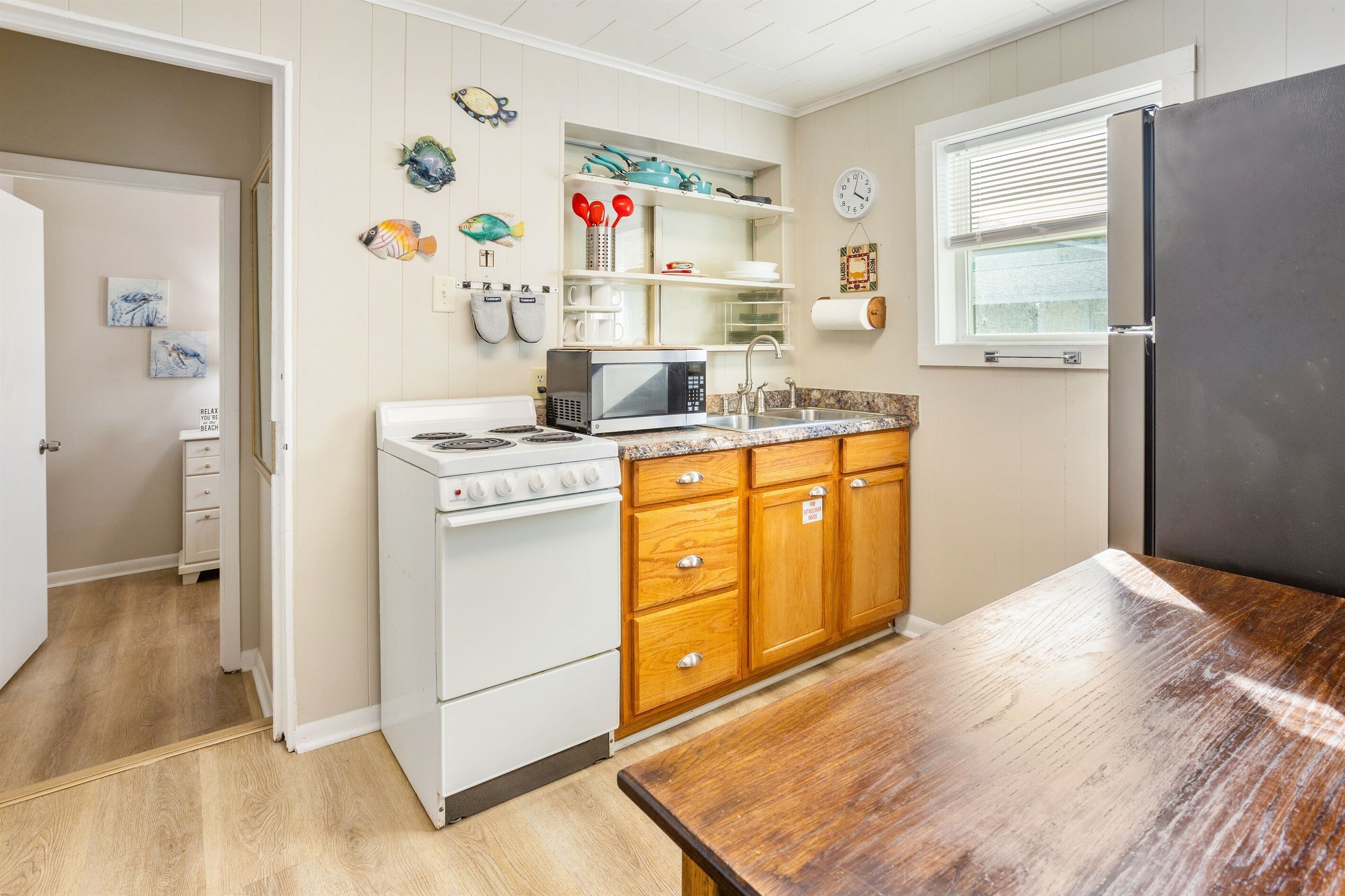 A compact kitchen with white appliances, wooden cabinets, and a wooden table.