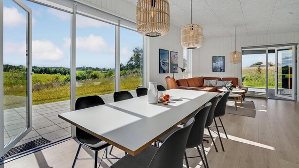 Una sala da pranzo moderna con un lungo tavolo, sedie nere e due lampade a sospensione.