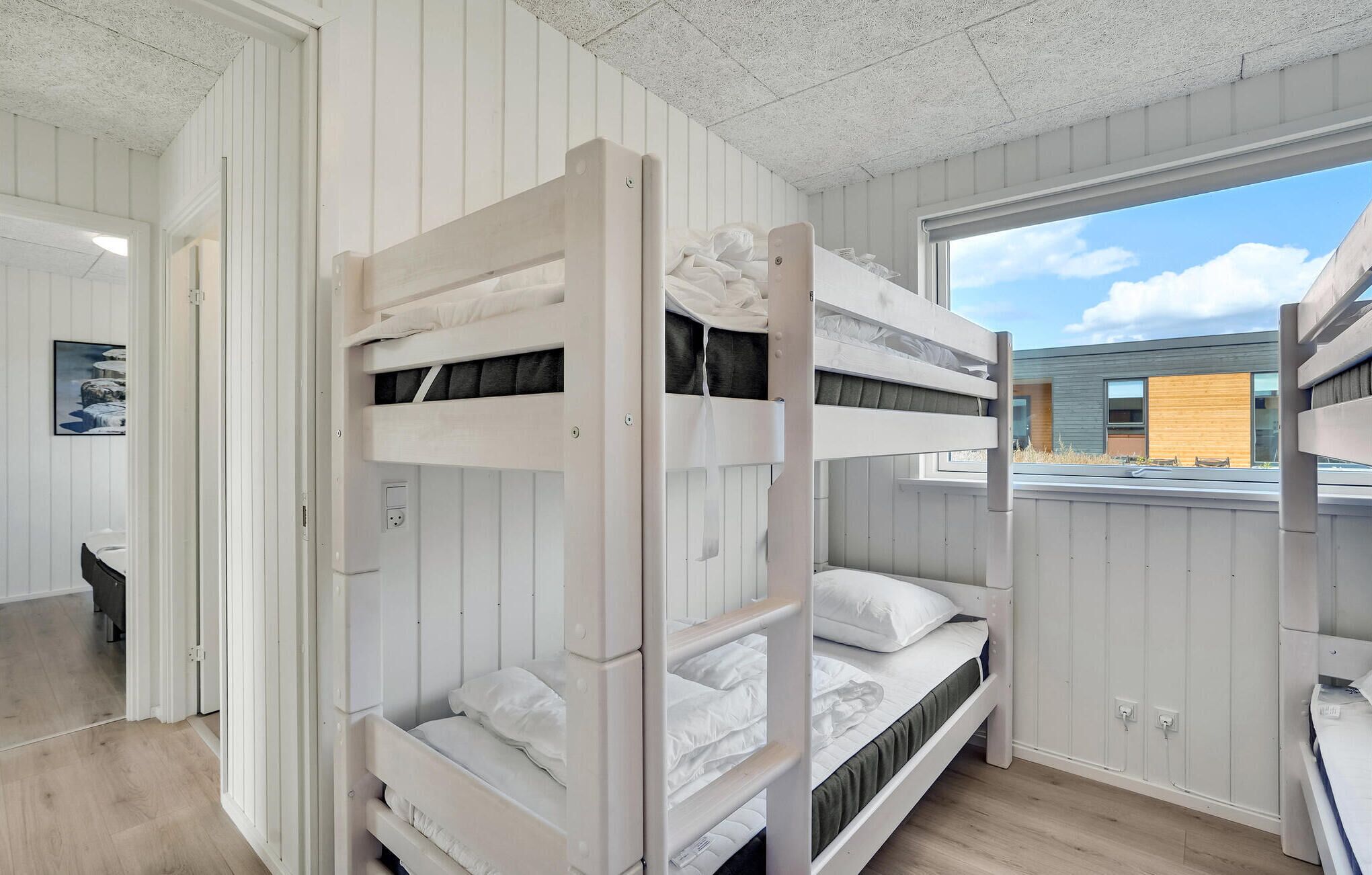 A bunk bed room with a window view of a modern building.