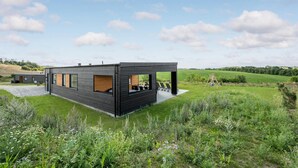 Una moderna casa a due piani con ampie finestre e un patio.