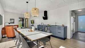 Una cucina moderna con isola centrale, mobili grigi e forno integrato. C'è un'area pranzo con un tavolo bianco e sedie grigie.