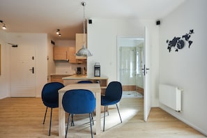 A modern kitchen with wooden cabinets, a dining table with blue chairs, and a hanging light fixture.