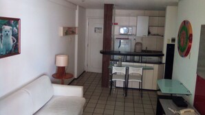 A compact living space with a kitchenette, a sofa, a dining table, and a chair. - Silva Hospedagem - Flat Number One (São Luís)