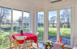 Een eetruimte met een tafel voor vier personen, grote ramen en uitzicht op een grasrijk landschap.