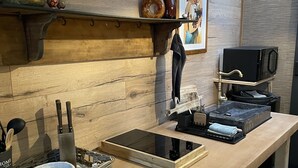 A modern kitchen with a wooden countertop, a black induction cooktop, a microwave, and a hanging towel rack. - Unique cosy Petite Maison with luxury jacuzzi (Hesdin)
