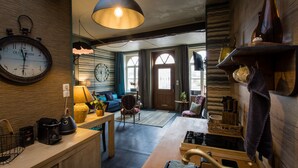 A cozy living room with a large clock, a sofa, a coffee table, and a fireplace. - Unique cosy Petite Maison with luxury jacuzzi (Hesdin)