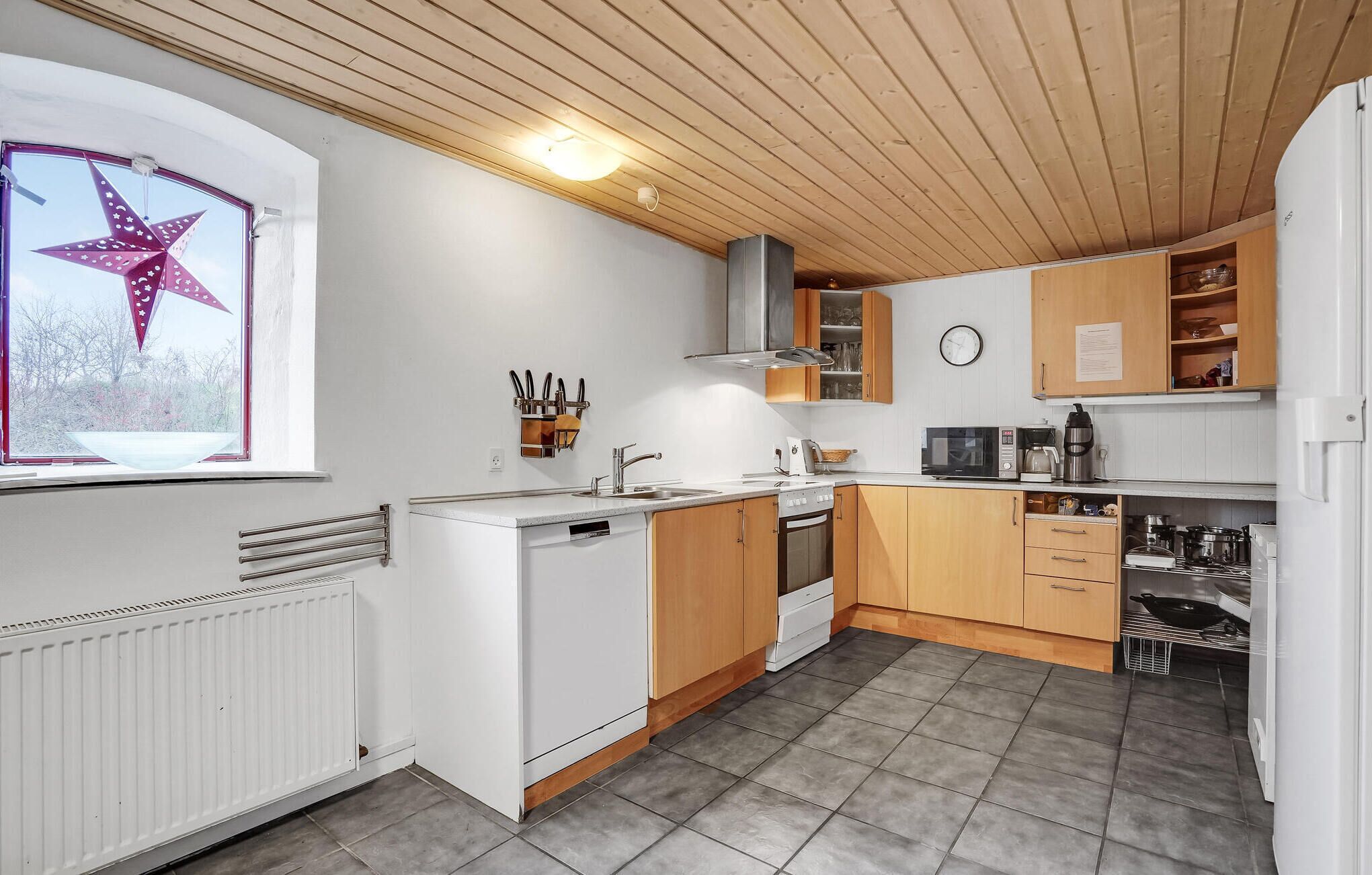 A compact kitchen with white appliances, wooden cabinets, and a star decoration on the window.