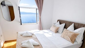 A bedroom with a bed, pillows, a window with a view, a mirror, and a wooden floor. - Lovely home in Jesenice with sauna (Jesenice)
