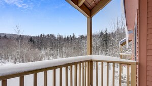 A wooden balcony with snow-covered railings and a view of a snowy forest. - Trail Creek 12 on the ski back trail with an indoor pool Next to Golf course (Killington)