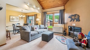 A cozy living room with a grey sofa, a small ottoman, a fireplace, and a bear-themed wall decoration. - Trail Creek 12 on the ski back trail with an indoor pool Next to Golf course (Killington)