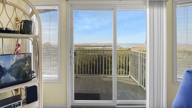 A room with a large sliding glass door leading to a balcony with a view of the beach and ocean. - Playa Flamingo 104-Bayside 83rd St, Free WiFi, Pool, Elev, W/D, AC (Ocean City)