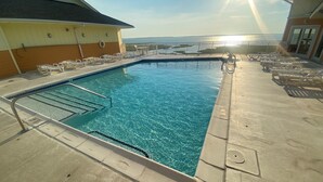 A swimming pool with a view of the ocean, surrounded by lounge chairs and a deck area. - Playa Flamingo 104-Bayside 83rd St, Free WiFi, Pool, Elev, W/D, AC (Ocean City)