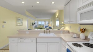 A modern kitchen with a central island, white cabinetry, and a built-in stove. - Playa Flamingo 104-Bayside 83rd St, Free WiFi, Pool, Elev, W/D, AC (Ocean City)