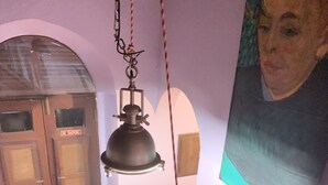Een trap met een hangende lantaarn, een houten deur met een 'Niet roken'-bord en een lijst met een kunstwerk aan de muur.